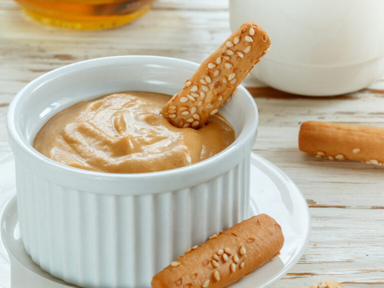 Ramequin de sauce à la moutarde et au miel dans lequel trempe un gressin au sésame