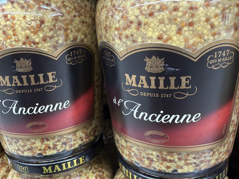 Bocaux de moutarde à l'ancienne Maille en rayon, dont les grains se voient à travers le verre
