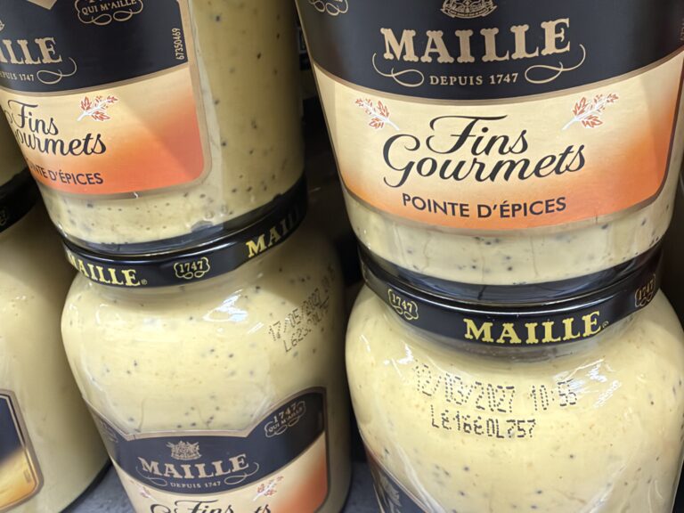 Pots de Maille Fins Gourmets pointe d'épices en rayon, avec la date 12/03/2027 imprimée sur le verre, sous le couvercle